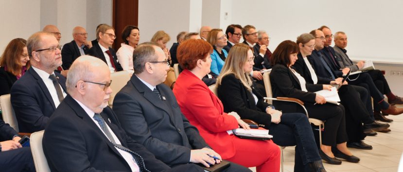 Kilkadziesiąt osób siedzi na sali.