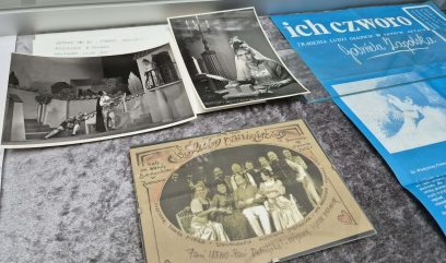 W gablocie znajdują się czarno-białe zabytkowe zdjęcia scen teatralnych i aktorów, odręczne zdjęcie z podpisami i serduszkami oraz niebieski program lub ulotka zatytułowana ich czworo z dodatkowym polskim tekstem. Dokumenty są ułożone jeden na drugim.
