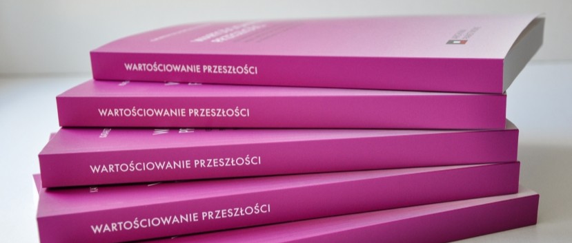 Pięć ułożonych w stos różowych książek z białym polskim napisem WARTOŚCIOWANIE PRZESZŁOŚCI na grzbietach. Książki są starannie ułożone, każda leży płasko i lekko przekrzywiona, z częściowo widoczną górną okładką. Tło jest białe.